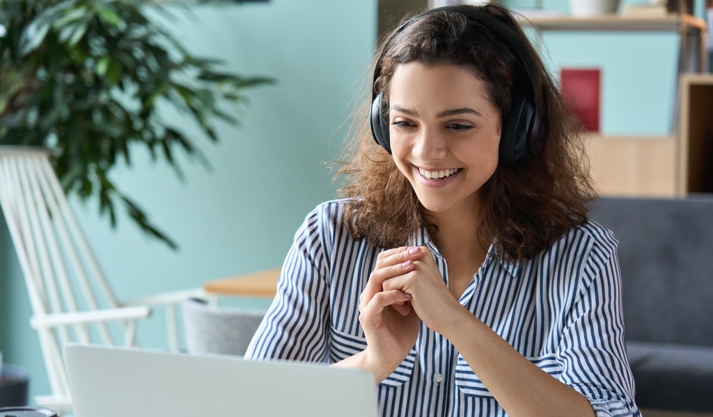 Curso de inglês - Mulher jovem sorrindo durante uma chamada de vídeo no notebook